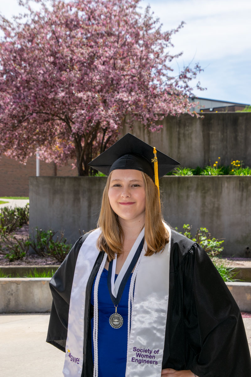 graduate in front of flowering tree