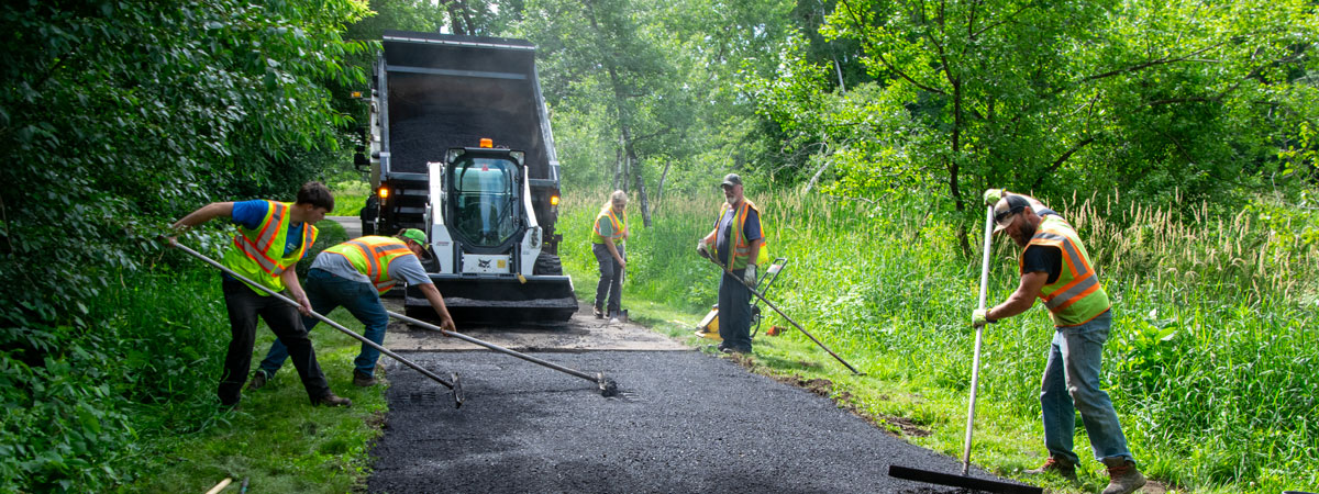 workers patching asphalt path in park